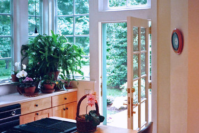 Inspiration for a transitional single-wall medium tone wood floor eat-in kitchen remodel in Philadelphia with shaker cabinets, light wood cabinets, laminate countertops, black appliances, an island, a double-bowl sink and white backsplash