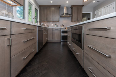 Inspiration for a modern l-shaped dark wood floor and brown floor kitchen remodel in DC Metro with an undermount sink, flat-panel cabinets, gray cabinets, quartzite countertops, gray backsplash, glass tile backsplash, stainless steel appliances, an island and white countertops