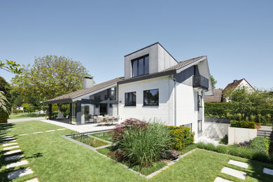 Mittelgroßes Einfamilienhaus mit Steinfassade, weißer Fassadenfarbe, Ziegeldach, grauem Dach und Verschalung in Dortmund