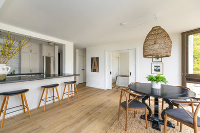 Example of a small minimalist u-shaped vinyl floor and brown floor eat-in kitchen design in Hawaii with a drop-in sink, shaker cabinets, white cabinets, soapstone countertops, white backsplash, subway tile backsplash, stainless steel appliances, an island and black countertops