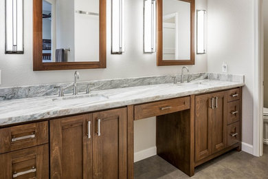 Mid-sized transitional master porcelain tile and gray tile porcelain tile and brown floor bathroom photo in Phoenix with shaker cabinets, medium tone wood cabinets, a two-piece toilet, white walls, an undermount sink and granite countertops
