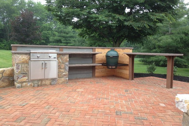 This is an example of a large traditional backyard patio in Philadelphia with an outdoor kitchen and brick pavers.