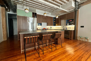 Example of a large trendy l-shaped medium tone wood floor and exposed beam eat-in kitchen design in Boston with an undermount sink, medium tone wood cabinets, quartz countertops, white backsplash, ceramic backsplash, stainless steel appliances, an island and gray countertops