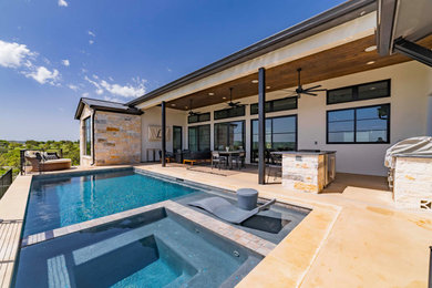 Hot tub - large modern backyard stamped concrete and rectangular hot tub idea in Austin