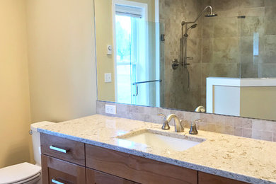 Corner shower - large craftsman master beige tile and porcelain tile porcelain tile and beige floor corner shower idea in Seattle with shaker cabinets, brown cabinets, a one-piece toilet, yellow walls, an undermount sink, quartzite countertops and a hinged shower door