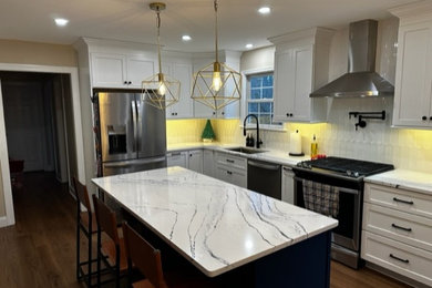 This is an example of a beach style l-shaped eat-in kitchen in Philadelphia with an undermount sink, shaker cabinets, white cabinets, quartz benchtops, white splashback, porcelain splashback, stainless steel appliances, with island and white benchtop.