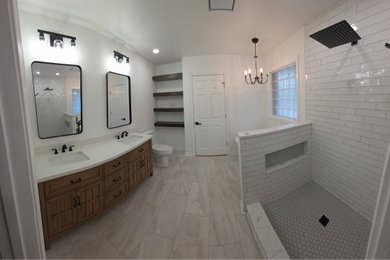 Example of a master double-sink bathroom design in Charlotte with medium tone wood cabinets, a hinged shower door, white countertops, a niche and a freestanding vanity