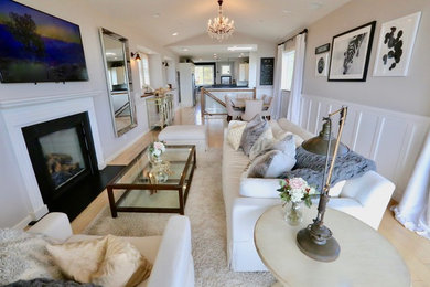 Large beach style open concept light wood floor and brown floor living room photo in Seattle with white walls, a standard fireplace, a wood fireplace surround and a wall-mounted tv