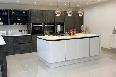 Photo of a large contemporary l-shaped open plan kitchen in London with a submerged sink, beaded cabinets, grey cabinets, quartz worktops, white splashback, granite splashback, black appliances, porcelain flooring, an island, white floors, white worktops and a coffered ceiling.