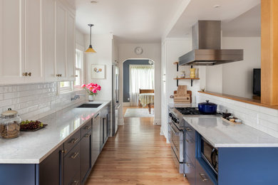 Eat-in kitchen - mid-sized traditional galley medium tone wood floor and brown floor eat-in kitchen idea in Portland with an undermount sink, shaker cabinets, blue cabinets, quartz countertops, white backsplash, subway tile backsplash, stainless steel appliances, no island and white countertops
