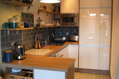 Inspiration for a medium sized rustic u-shaped open plan kitchen in Glasgow with an integrated sink, flat-panel cabinets, white cabinets, laminate countertops, blue splashback, ceramic splashback, stainless steel appliances, terracotta flooring and a breakfast bar.