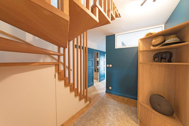 Imagen de distribuidor contemporáneo grande con paredes azules, suelo de madera clara y puerta simple