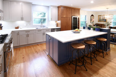 Example of a mid-sized trendy l-shaped medium tone wood floor and brown floor eat-in kitchen design in Raleigh with flat-panel cabinets, quartz countertops, white backsplash, ceramic backsplash, an island and white countertops