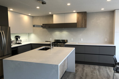 Example of a mid-sized minimalist kitchen design in Calgary with flat-panel cabinets, gray cabinets, quartz countertops and an island