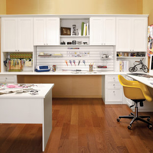 This is an example of a mid-sized contemporary craft room in Nashville with medium hardwood floors, no fireplace, yellow walls and a built-in desk.