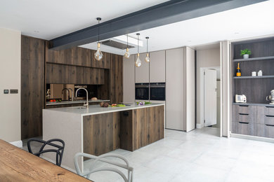 Design ideas for a large contemporary l-shaped open plan kitchen in London with an integrated sink, flat-panel cabinets, concrete benchtops, brown splashback, mirror splashback, black appliances, with island and white benchtop.