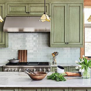 Свежая идея для дизайна: прямая кухня-гостиная среднего размера в стиле кантри с врезной раковиной, фасадами с утопленной филенкой, зелеными фасадами, столешницей из кварцевого агломерата, зеленым фартуком, фартуком из стеклянной плитки, техникой под мебельный фасад, паркетным полом среднего тона, островом, коричневым полом и серой столешницей - отличное фото интерьера