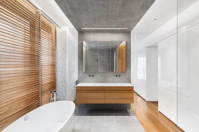 Inspiration for a mid-sized contemporary master gray tile ceramic tile bathroom remodel in Montreal with flat-panel cabinets, light wood cabinets, gray walls and an integrated sink