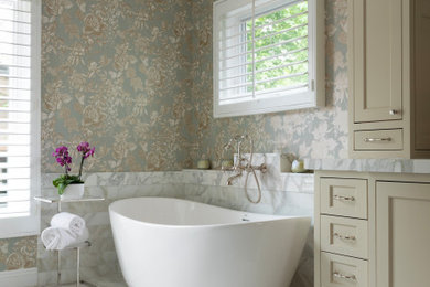 Freestanding bathtub - large traditional master white tile and marble tile marble floor, white floor, double-sink and wallpaper freestanding bathtub idea in Orange County with recessed-panel cabinets, white cabinets, blue walls, an undermount sink, marble countertops, a hinged shower door, white countertops and a built-in vanity