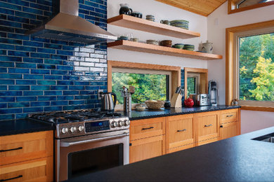 Inspiration for a light wood floor and vaulted ceiling kitchen remodel in Vancouver with an undermount sink, granite countertops, blue backsplash, ceramic backsplash, stainless steel appliances, an island and black countertops