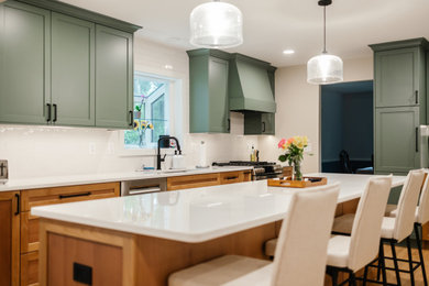 Large transitional light wood floor and brown floor kitchen photo in Baltimore with an undermount sink, recessed-panel cabinets, green cabinets, quartz countertops, white backsplash, porcelain backsplash, stainless steel appliances, an island and white countertops