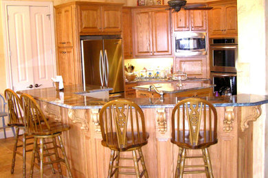 Example of an eat-in kitchen design in Dallas with raised-panel cabinets, light wood cabinets and an island