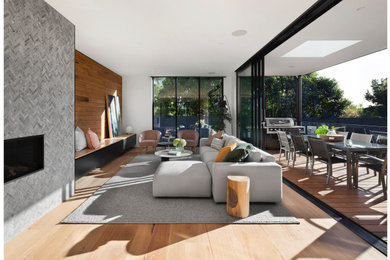 Photo of a contemporary open concept living room in Wollongong with white walls, medium hardwood floors, a ribbon fireplace and wood walls.