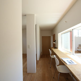 他の地域のモダンスタイルのおしゃれなホームオフィス・仕事部屋 (白い壁、無垢フローリング、造り付け机、茶色い床) の写真