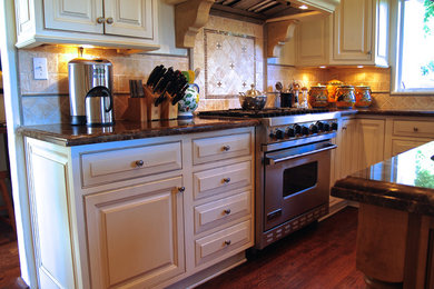 Mid-sized elegant u-shaped medium tone wood floor kitchen pantry photo in Santa Barbara with a double-bowl sink, beaded inset cabinets, white cabinets, granite countertops, multicolored backsplash, paneled appliances and an island