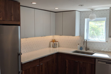 Example of a mid-century modern ceramic tile and gray floor kitchen design in Philadelphia with an undermount sink, flat-panel cabinets, medium tone wood cabinets, quartz countertops, white backsplash, ceramic backsplash, stainless steel appliances and white countertops