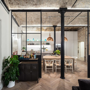 Photo of an industrial open plan dining in London with light hardwood floors.