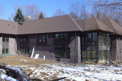 Diseño de fachada de casa marrón y marrón contemporánea grande de una planta con revestimientos combinados, tejado a cuatro aguas y tejado de teja de madera