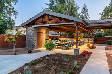Large mountain style backyard concrete patio kitchen photo in Other with a roof extension