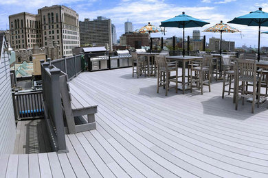 Example of a large minimalist rooftop outdoor kitchen deck design in Portland Maine with a roof extension
