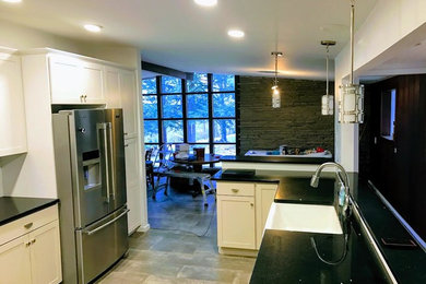 Inspiration for a timeless u-shaped eat-in kitchen remodel in Philadelphia with a farmhouse sink, shaker cabinets, white cabinets and stainless steel appliances