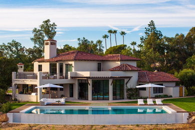 Example of a large tuscan beige two-story stucco house exterior design in San Diego with a tile roof and a red roof
