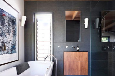 This is an example of a contemporary master bathroom in Melbourne with flat-panel cabinets, medium wood cabinets, a freestanding tub, a curbless shower, black tile and white walls.