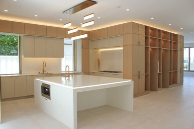 Photo of a medium sized modern l-shaped kitchen pantry in Orange County with a belfast sink, shaker cabinets, light wood cabinets, laminate countertops, white splashback, ceramic splashback, stainless steel appliances, ceramic flooring, an island, multi-coloured floors, white worktops and a vaulted ceiling.