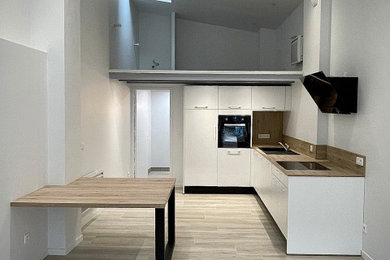 低価格の中くらいな北欧スタイルのおしゃれなキッチン (木材カウンター、木材のキッチンパネル、黒い調理設備、淡色無垢フローリング) の写真