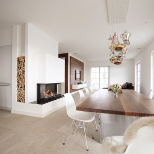 Exemple d'une grande salle à manger ouverte sur la cuisine avec un mur blanc, un sol en ardoise, une cheminée double-face, un manteau de cheminée en plâtre et un sol beige.