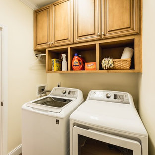 Design ideas for a small classic galley utility room in Charleston with raised-panel cabinets, medium wood cabinets, laminate floors, brown floors, beige walls and a side by side washer and dryer.