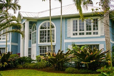 Large blue two-story wood exterior home photo in Miami with a hip roof