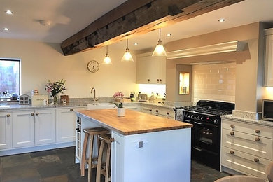 Photo of a traditional kitchen in West Midlands with shaker cabinets, white cabinets, white splashback, ceramic splashback and an island.