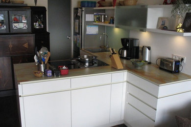 Offene, Mittelgroße Klassische Küche in L-Form mit integriertem Waschbecken, flächenbündigen Schrankfronten, weißen Schränken, Arbeitsplatte aus Holz, Küchenrückwand in Weiß, Rückwand aus Holz, Küchengeräten aus Edelstahl, dunklem Holzboden, Halbinsel und braunem Boden in Bremen