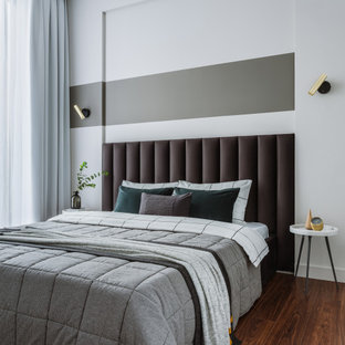 Modelo de dormitorio principal, contemporáneo, de tamaño medio, con paredes grises, suelo laminado y suelo marrón