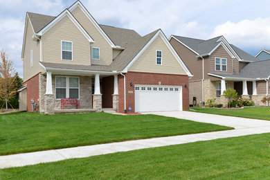 Example of a large arts and crafts beige two-story mixed siding gable roof design in Detroit