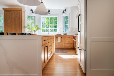 Eat-in kitchen - large transitional l-shaped light wood floor eat-in kitchen idea in Boston with an undermount sink, shaker cabinets, quartz countertops, white backsplash, quartz backsplash, stainless steel appliances, an island and white countertops
