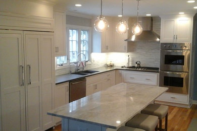 Inspiration for a mid-sized transitional l-shaped light wood floor eat-in kitchen remodel in Newark with a double-bowl sink, shaker cabinets, white cabinets, solid surface countertops, multicolored backsplash, stone tile backsplash, stainless steel appliances and an island