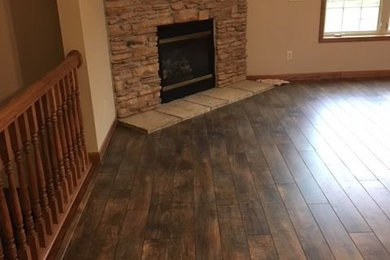Inspiration for a large rural open plan games room in Cleveland with laminate floors, a corner fireplace, a stone fireplace surround and brown floors.