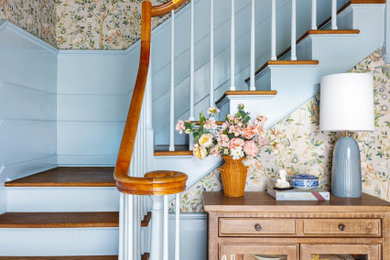 Diseño de escalera en L campestre grande con escalones de madera, contrahuellas de madera pintada, barandilla de madera y papel pintado